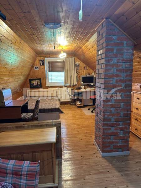 Attic room in a cabin with a wooden interior and a brick pillar.