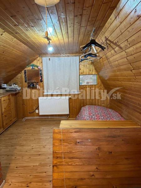A wooden interior of a cabin with a bed and a wardrobe makes the space under the roof cozy.