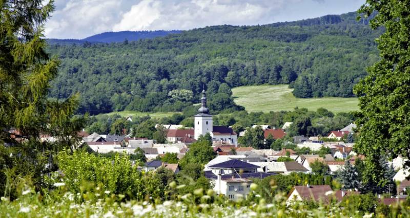 A picturesque panorama of Lutila with agricultural and forest lands and a church surrounded by green forests.