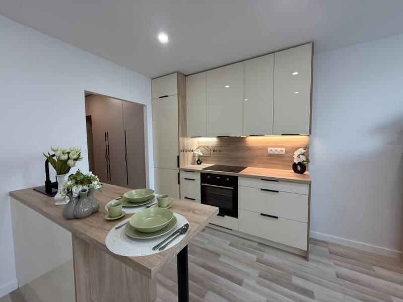 A kitchen in a studio apartment with modern furnishings and wooden elements.
