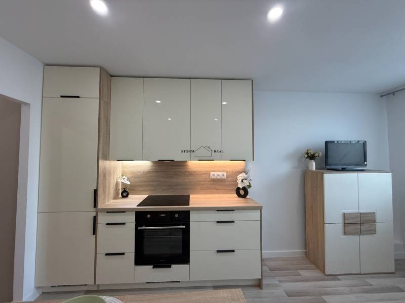 A kitchen unit in a one-room apartment with modern appliances and elegant storage space.