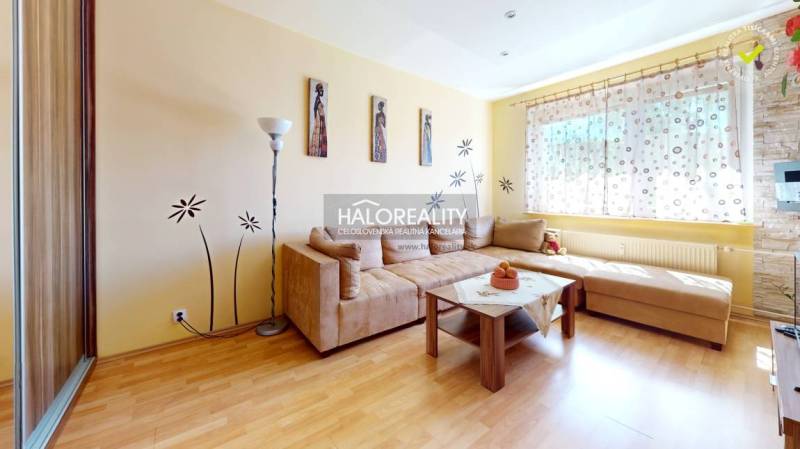 Living room with a sofa, decorations, and a large window in a 3-room apartment.