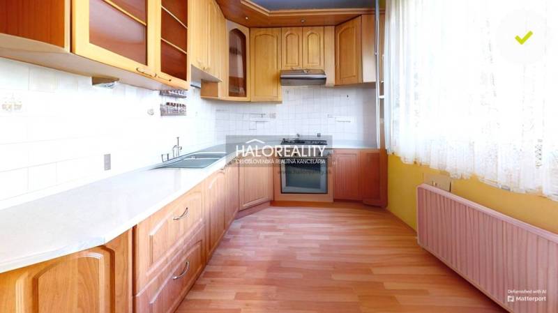 A kitchen with a wooden cabinet and appliances in a 3-room apartment, light tiles, curtains.