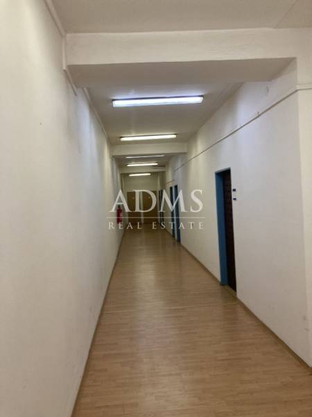 Narrow interior corridor with lights, wooden floor, and light walls in warehouses and halls.