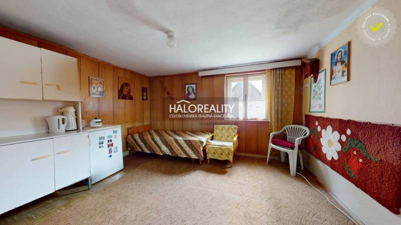 Interior of a family house with wooden paneling, simple furniture, and carpeted flooring.