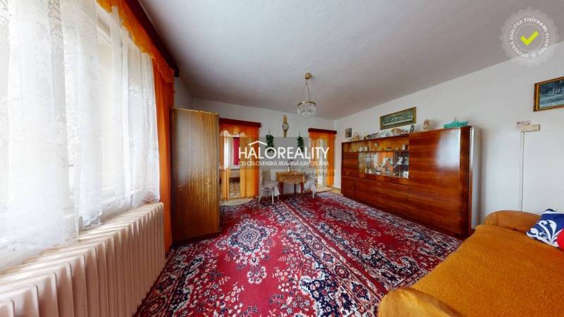 A living room in a family house with a red carpet and classic furniture.
