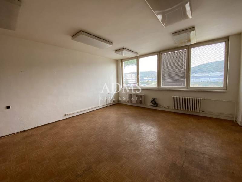 Empty office with wooden floor and large windows.