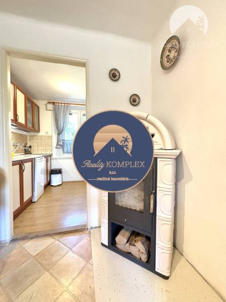 A fireplace in the interior of a cabin with a view of the kitchen and ceramic decorations on the wall.