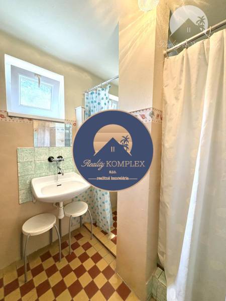 A bathroom in a cabin with a sink, shower, and a window for natural light.