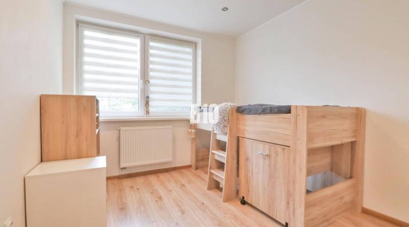 Wooden bed with a desk, cabinets, window with blinds, light flooring. 3-room apartment.