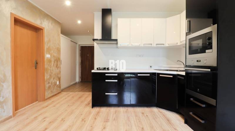 Kitchen in a 3-room apartment, black cabinets, built-in appliances, wooden floor.