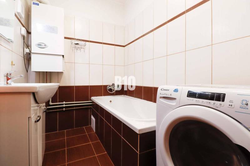 Bathroom in a 3-room apartment with a bathtub, washing machine, and sink.