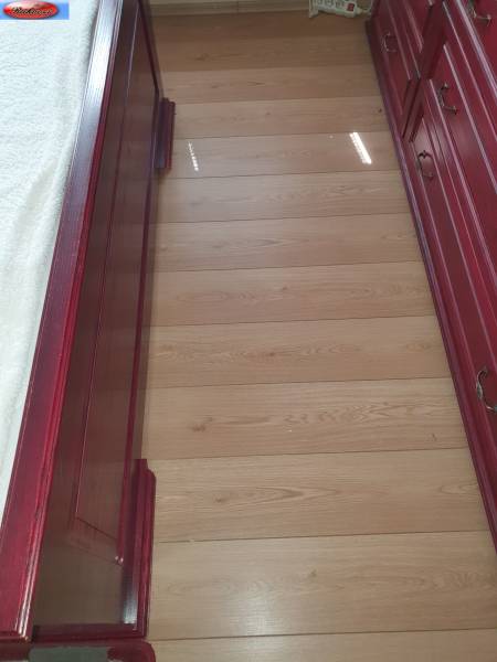 The floor in a 2-room apartment with red wooden furniture and a bed.