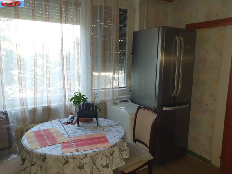 Kitchen in a 2-room apartment with a large refrigerator and a dining table.