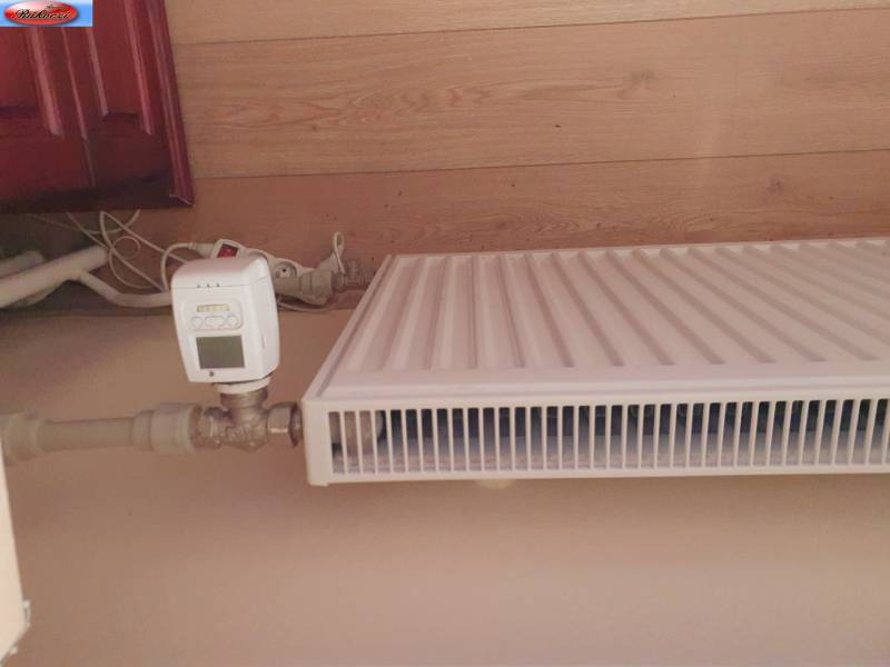 Radiator with a thermostat in a 2-room apartment with wooden walls.