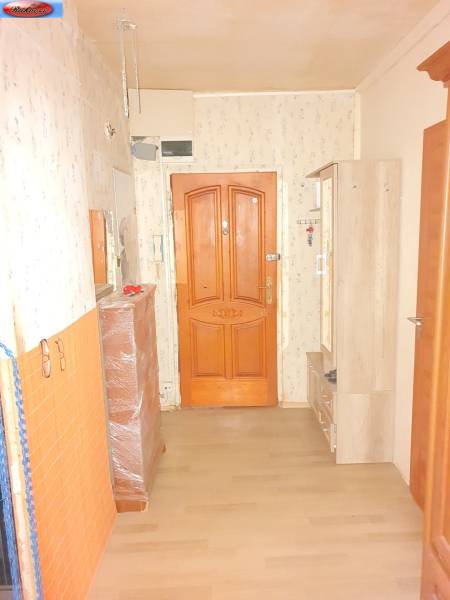 The hallway in the entrance of a 2-room apartment with wooden doors and simple furniture.