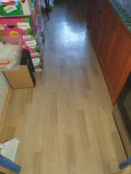 The floor in the kitchen of a 2-room apartment with boxes in a pile, wooden cabinets on the right.