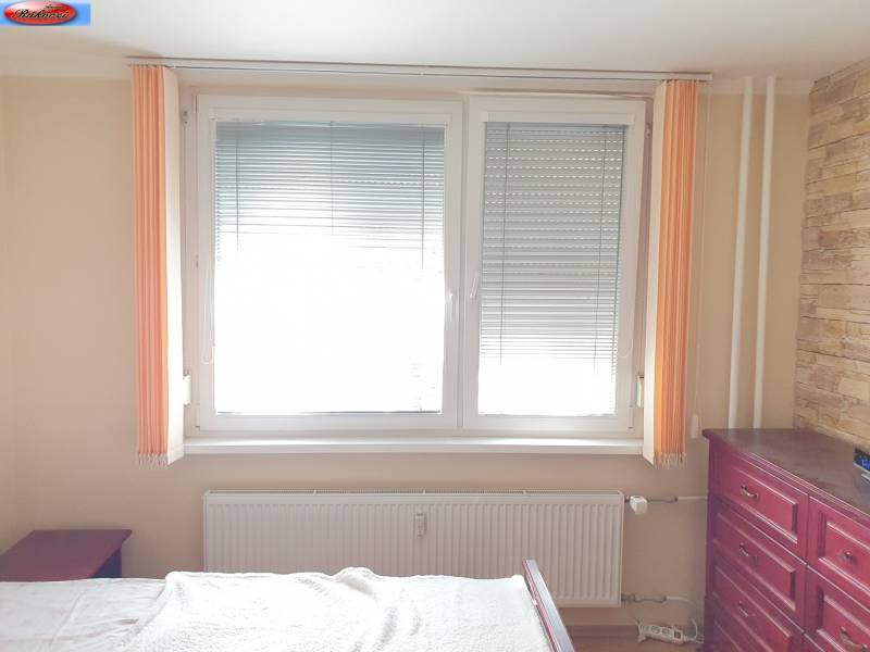 Bedroom in a 2-room apartment with a large window, radiator, and dresser.