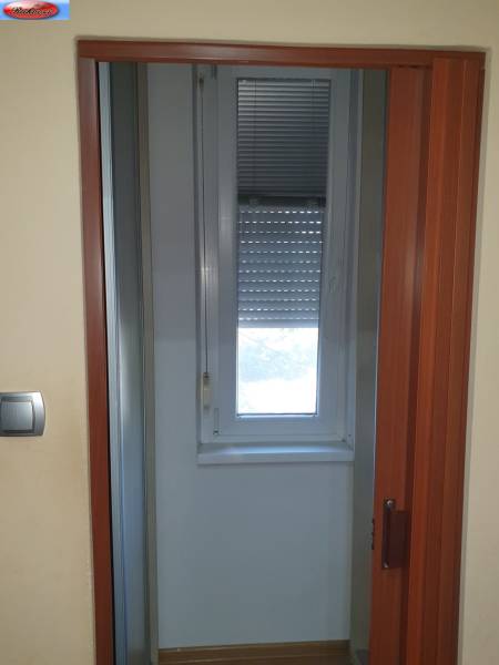 Sliding door and window with a blind in a 2-room apartment.