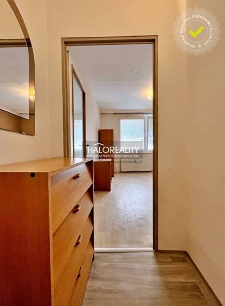 Studio apartment with a wooden dresser and a mirror, view of the room with windows.
