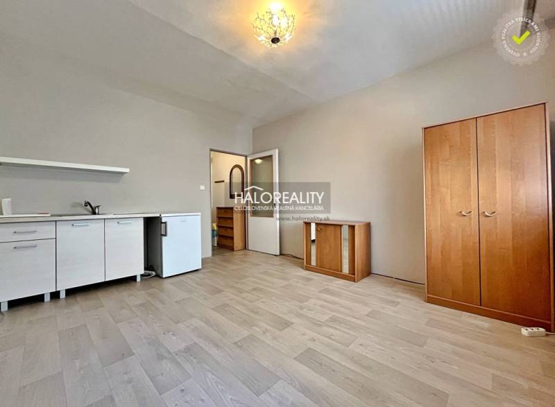 A studio apartment with a light interior, wooden flooring, and furniture in neutral colors.
