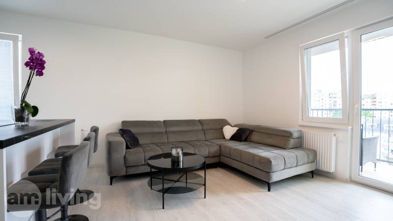Living room in a 3-room apartment with a comfortable gray sofa and a balcony.