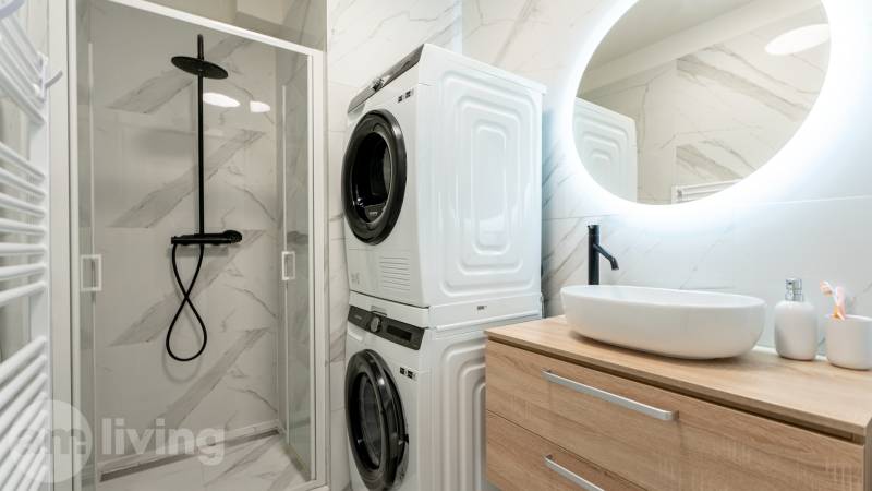 Bathroom with a washing machine, dryer, shower corner, and sink in a 3-room apartment.