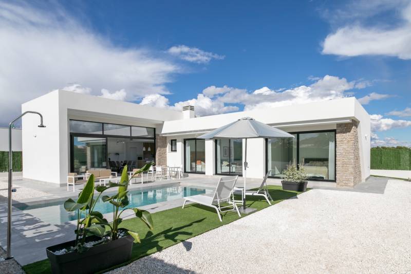 The villa in Calasparra has a swimming pool, a terrace with loungers, and a parasol under the blue sky.
