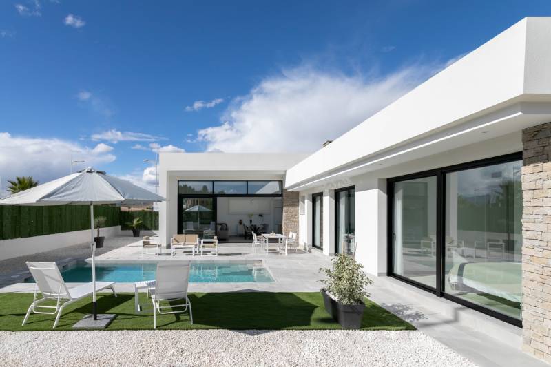 A villa in Calasparra with a swimming pool and garden seating under a sunshade.