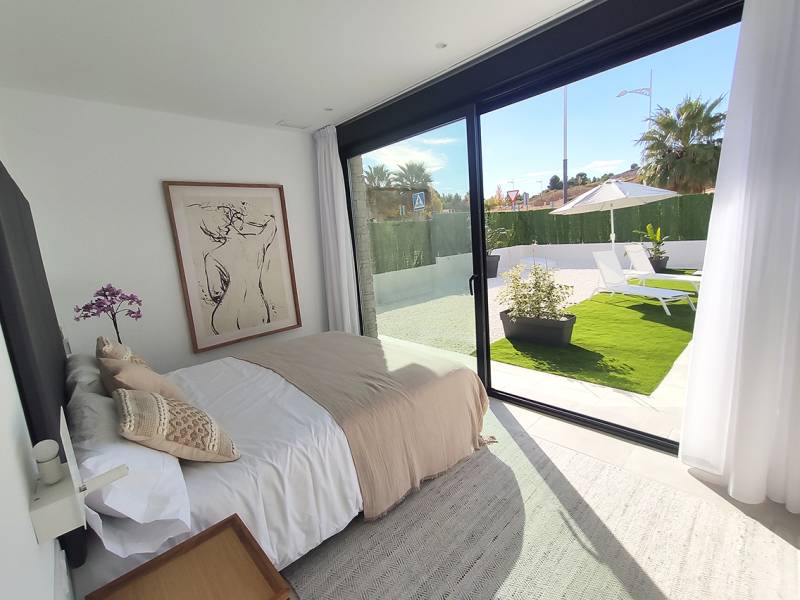 A bright interior of a villa with a bed, artwork, and a view of the garden.