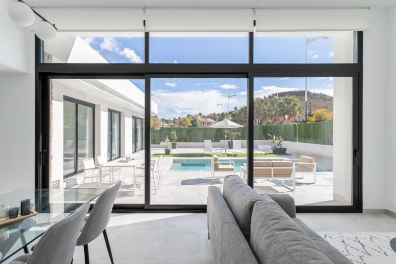 The interior of the villa with large glass doors leading to the terrace with a pool.