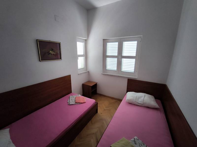 Two single beds side by side in a studio apartment, bright room with wooden floors.