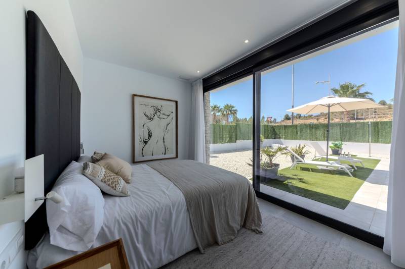 A bedroom in a villa with large windows and a view of the garden.