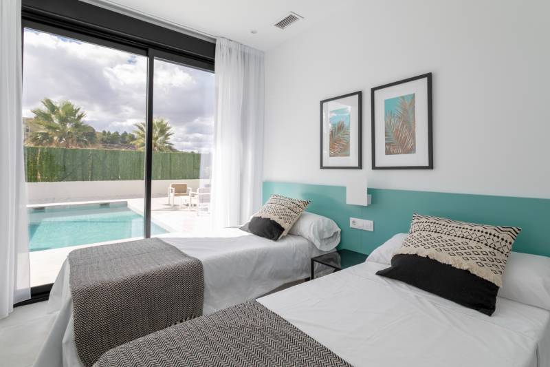 A bedroom in a villa with two beds, a view of the pool, and an outdoor terrace.