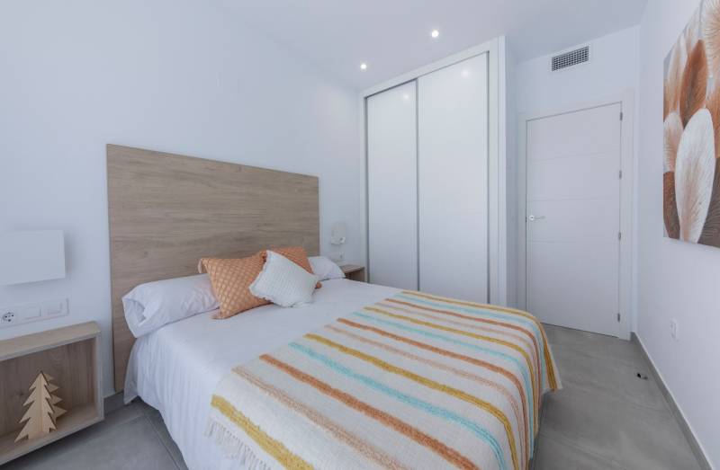 Bright bedroom in a villa with minimalist furniture, textile accessories, and a built-in wardrobe.