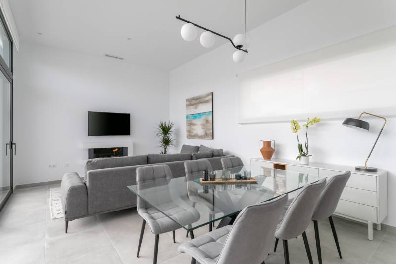 Living room in a villa with a glass table, gray armchairs, and decorations.