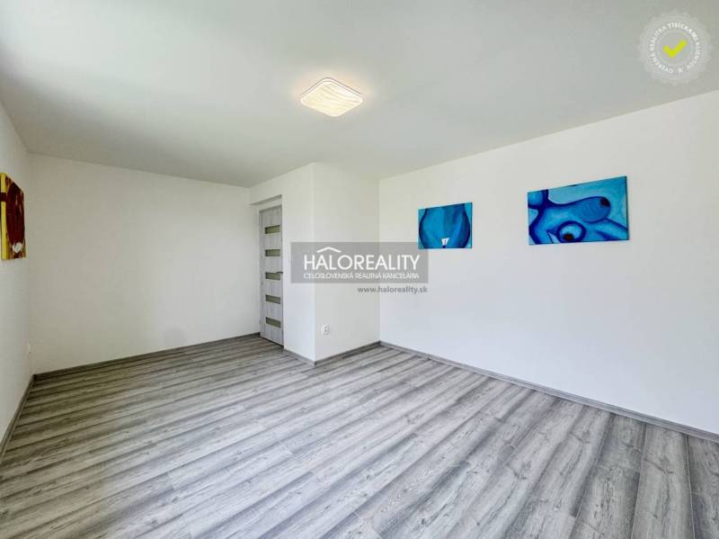A spacious room with wooden flooring and abstract paintings in a family house.