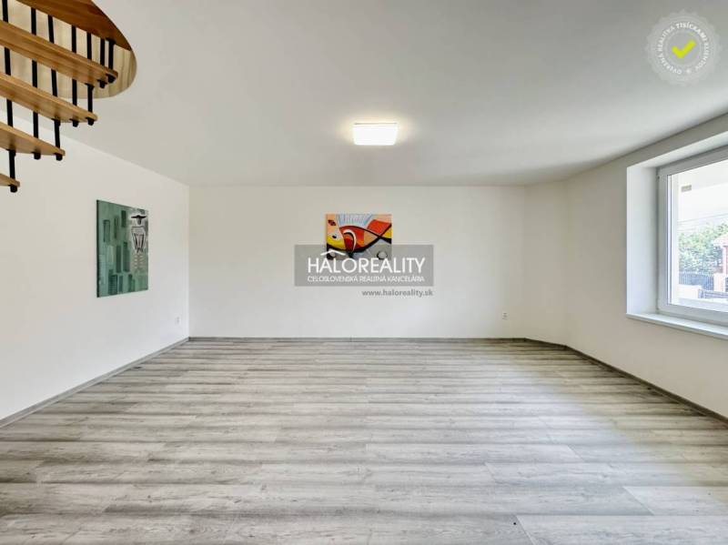 In the family house, there are wooden stairs, paintings on the walls, and a large window.