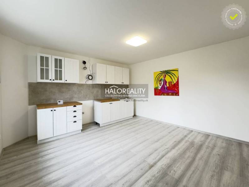 A clean space in a family house with white kitchen cabinets and a colorful painting.