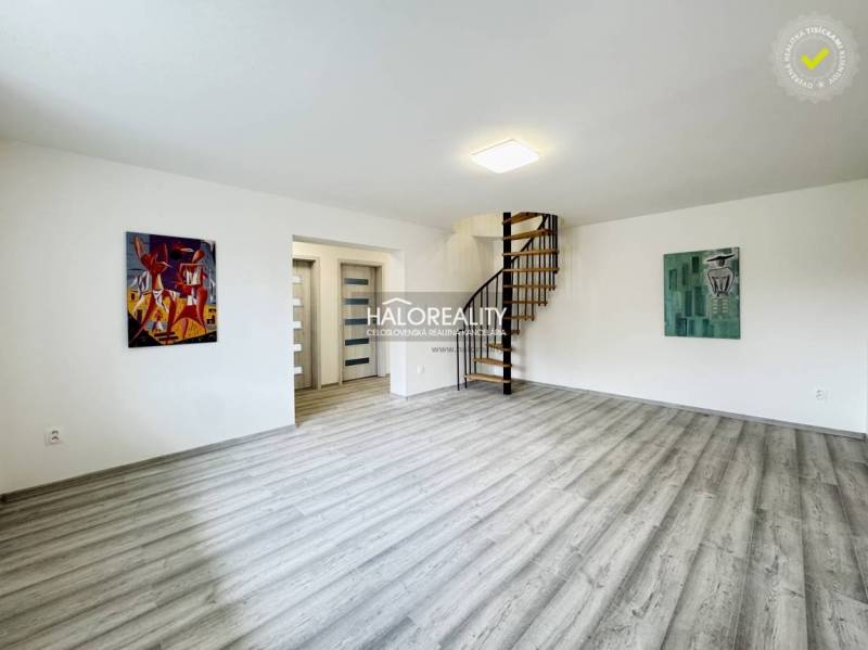 Living room in a family house with wooden stairs and artistic paintings on the walls.