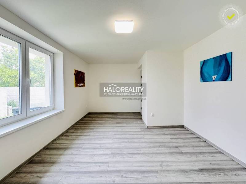 The interior of a family house room with a large window and abstract paintings on the walls.