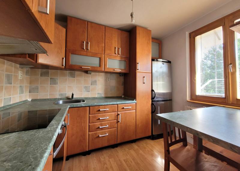 A kitchen with wooden cabinets and a dining table in a studio apartment.