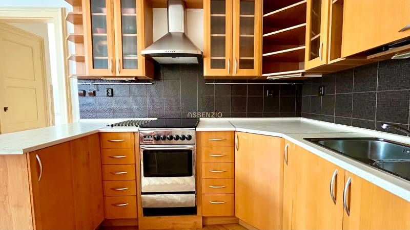 A kitchen in a 2-room apartment with wooden cabinets and dark tiles.