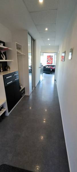 Interior of a family house with a long hallway, black cabinets, and part of the living room.