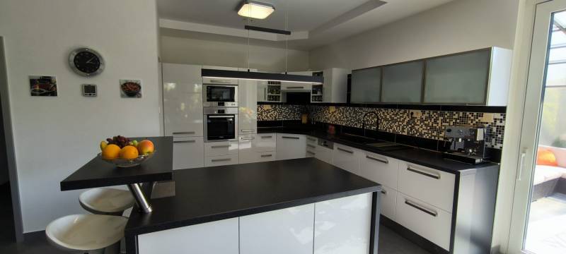 A kitchen in a family house with white cabinets and black and white mosaic tiles.