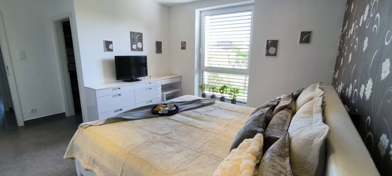 A bright bedroom with a bed and a television in a family house, decorations on the walls.