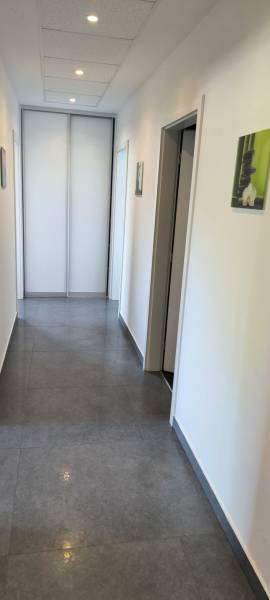 A hallway in a family house with tiles, light-colored walls, and pendant lighting.