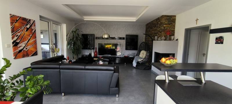 Living room in a family house with black sofa furniture and a TV on the wall.