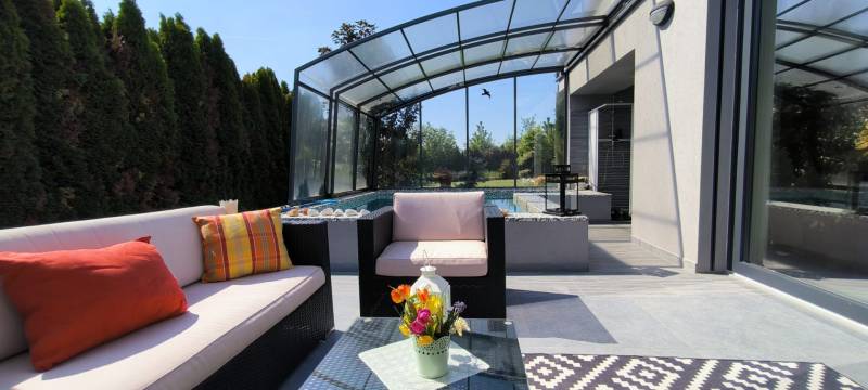 The terrace of a family house in Zurndorf with seating by the pool and glass sliding doors.