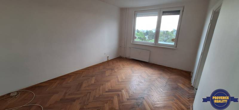 A room in a 3-bedroom apartment with a parquet floor and a large window.